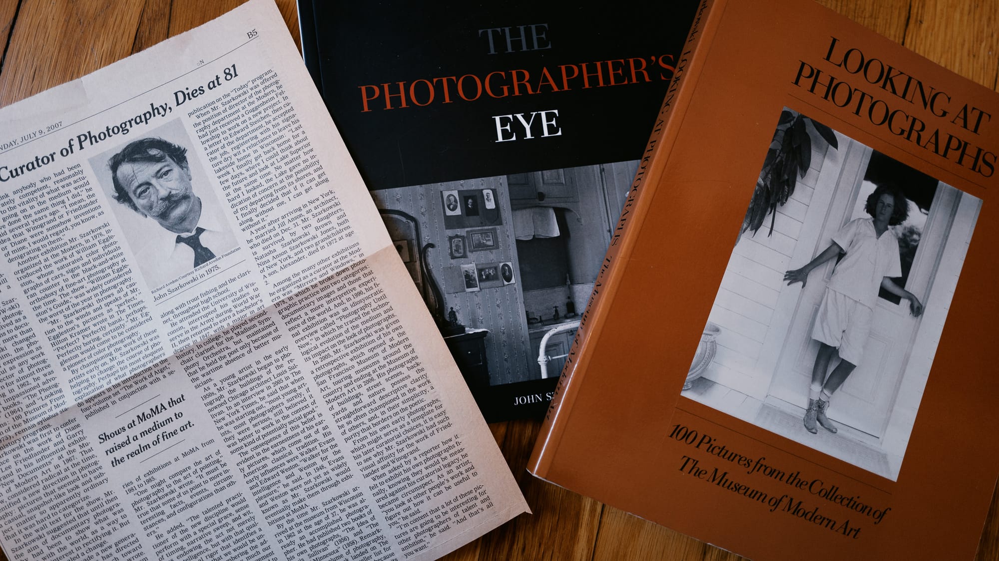 two books by John Szarkwoski next to a cut out of his obituary from the New York Times