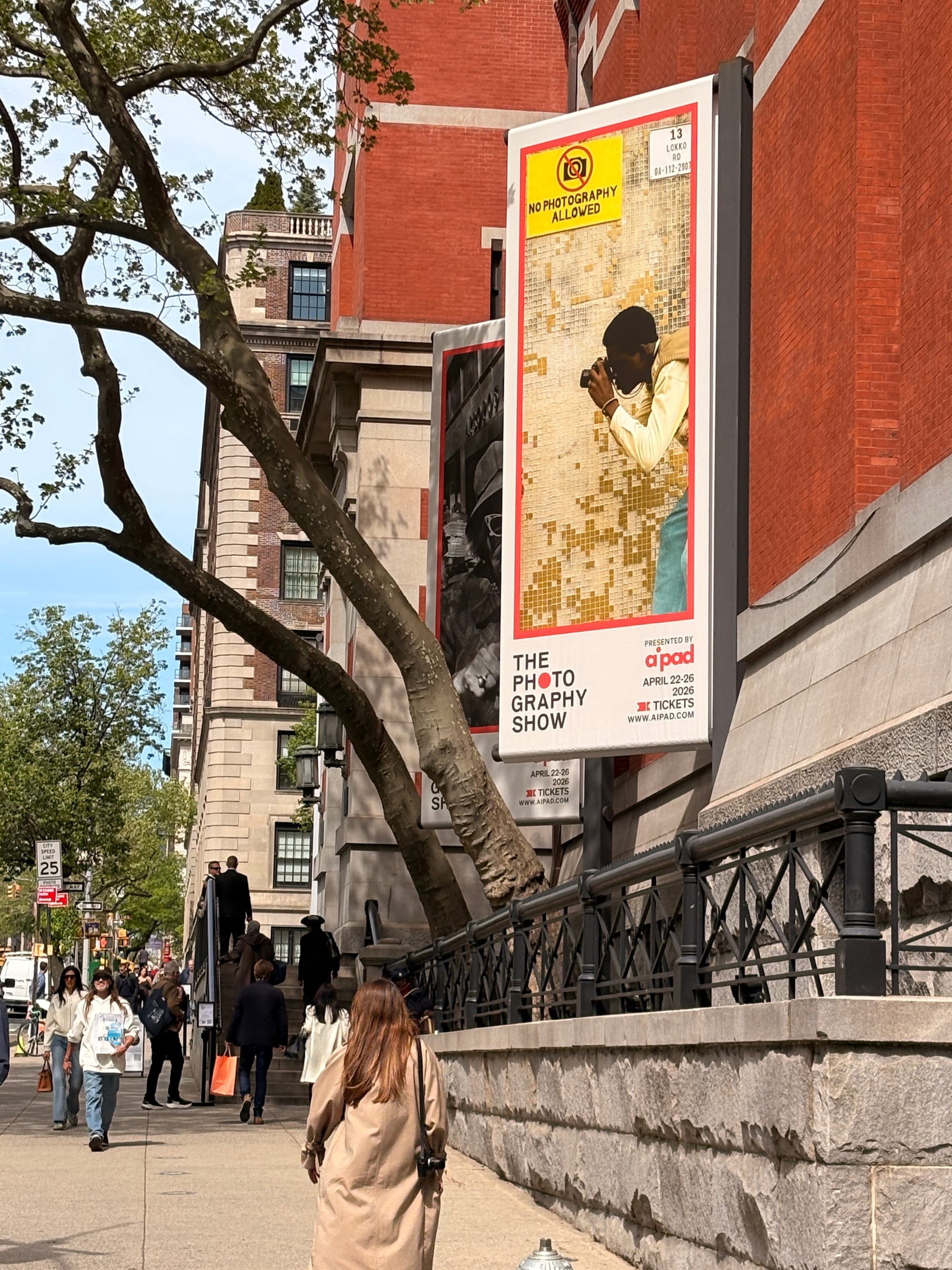 Entrance to Park Ave Armory with people walking in both directions and the AIPAD sign with The Photography Show is hanging on the side of the building.