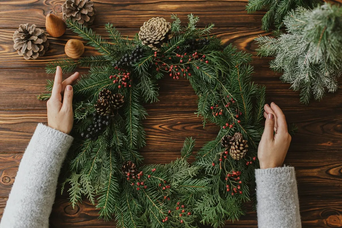 Person bereitet einen Adventskranz vor – Einstimmung auf das Adventsquiz.