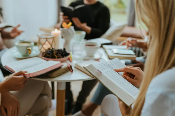Eine junge Frau macht sich Notizen in ihrer Bibel während eines Kleingruppengesprächs.