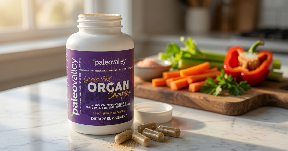 Paleovalley Grass Fed Organ Complex supplement bottle with capsules on a kitchen counter, surrounded by fresh vegetables