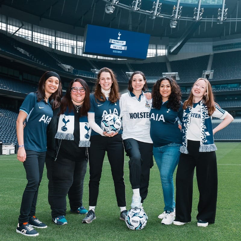 The founders of Women of the Lane pose for a photo in the stadium on the pitch. 