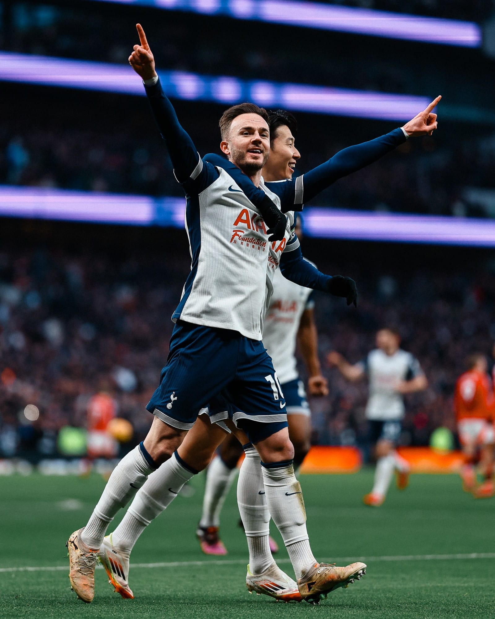 James Maddison holds up his hands with fingers pointed while receiving a one-armed hug from Son Heung-min.