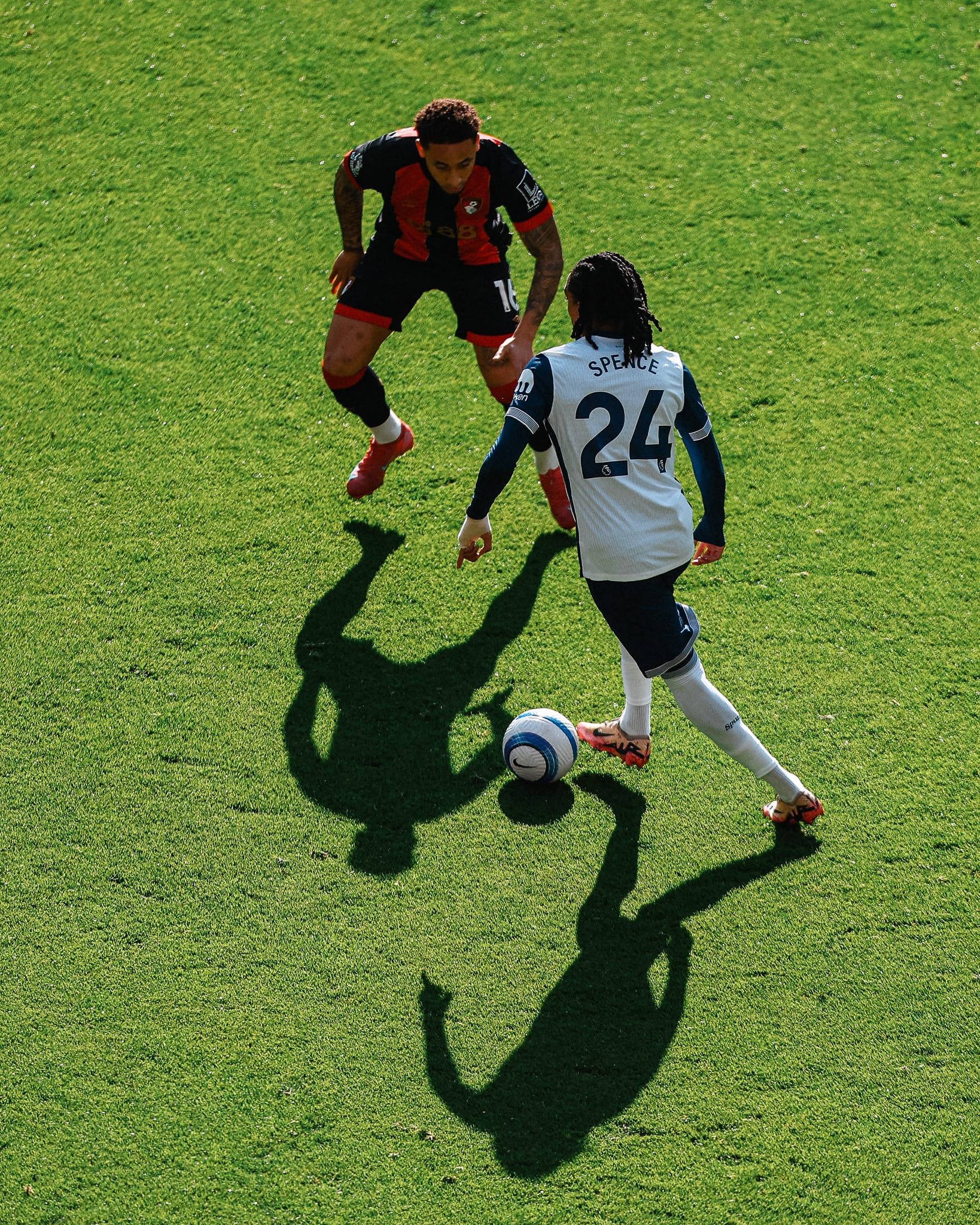 An aerial shot of Djed Spence taking on Marcus Tavernier, shadows on the grass below them.