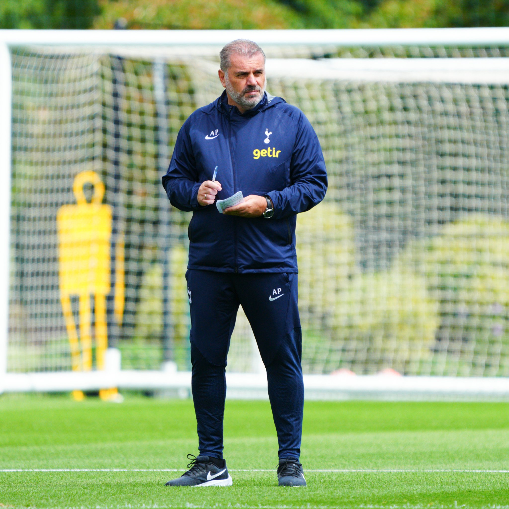 Ange Postecoglou standing in front of a goal and taking notes during a training session.