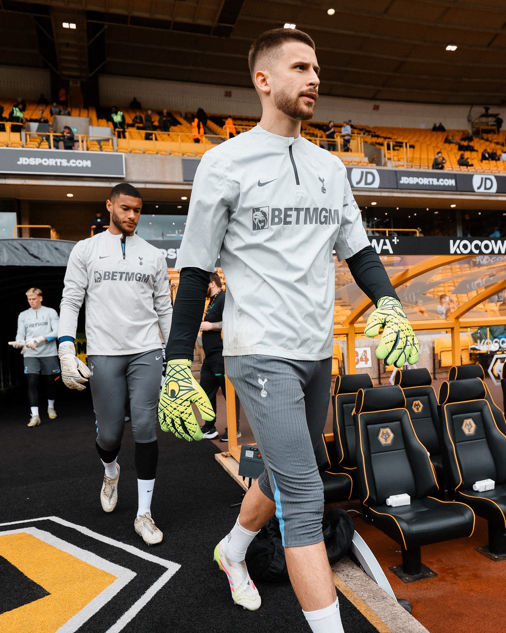 Guglielmo Vicario walks onto the pitch for warmups in his training gear, flanked by Brandon Austin and Antonín Kinský.