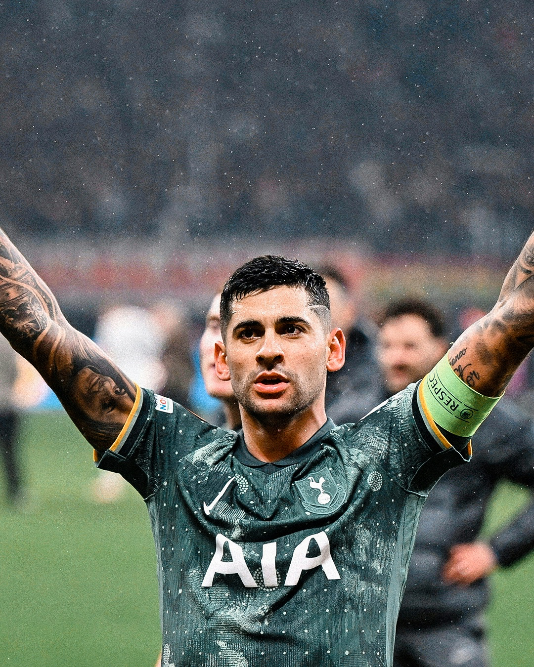 Cristian Romero holds his hands up in victory, wearing the captain's armband on his left bicep.