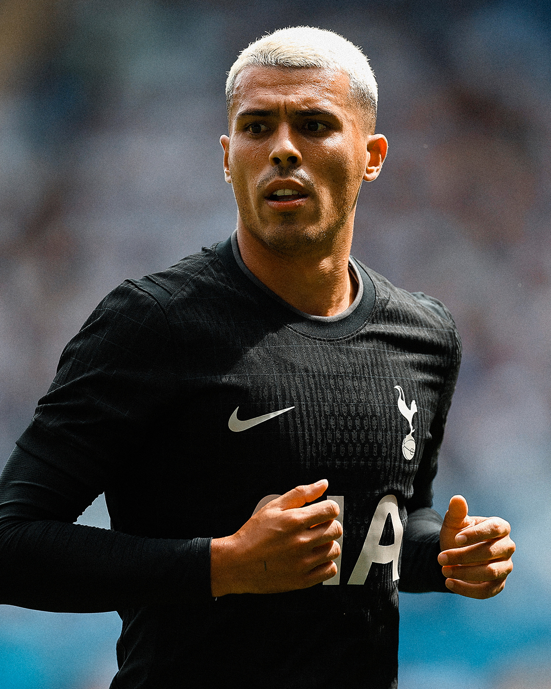 Pedro Porro, newly blonde, wears the 2025/26 away kit, black with a subtle grid and white logo/sponsor graphics.