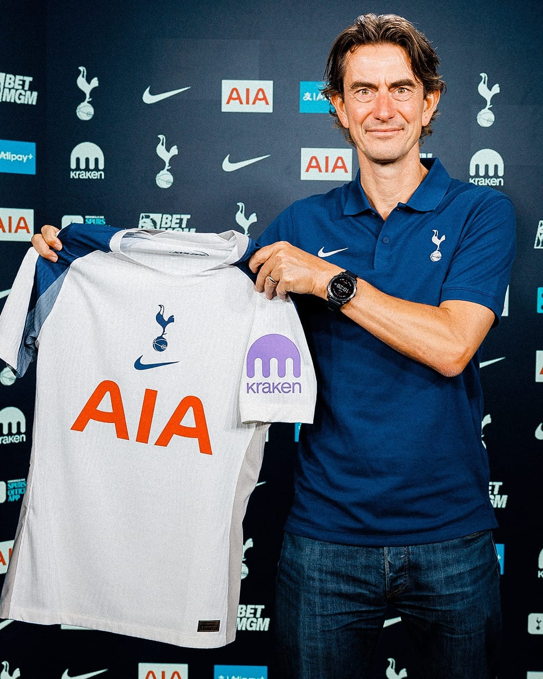 Thomas Frank smiles and holds up a 2025/26 Tottenham home shirt.