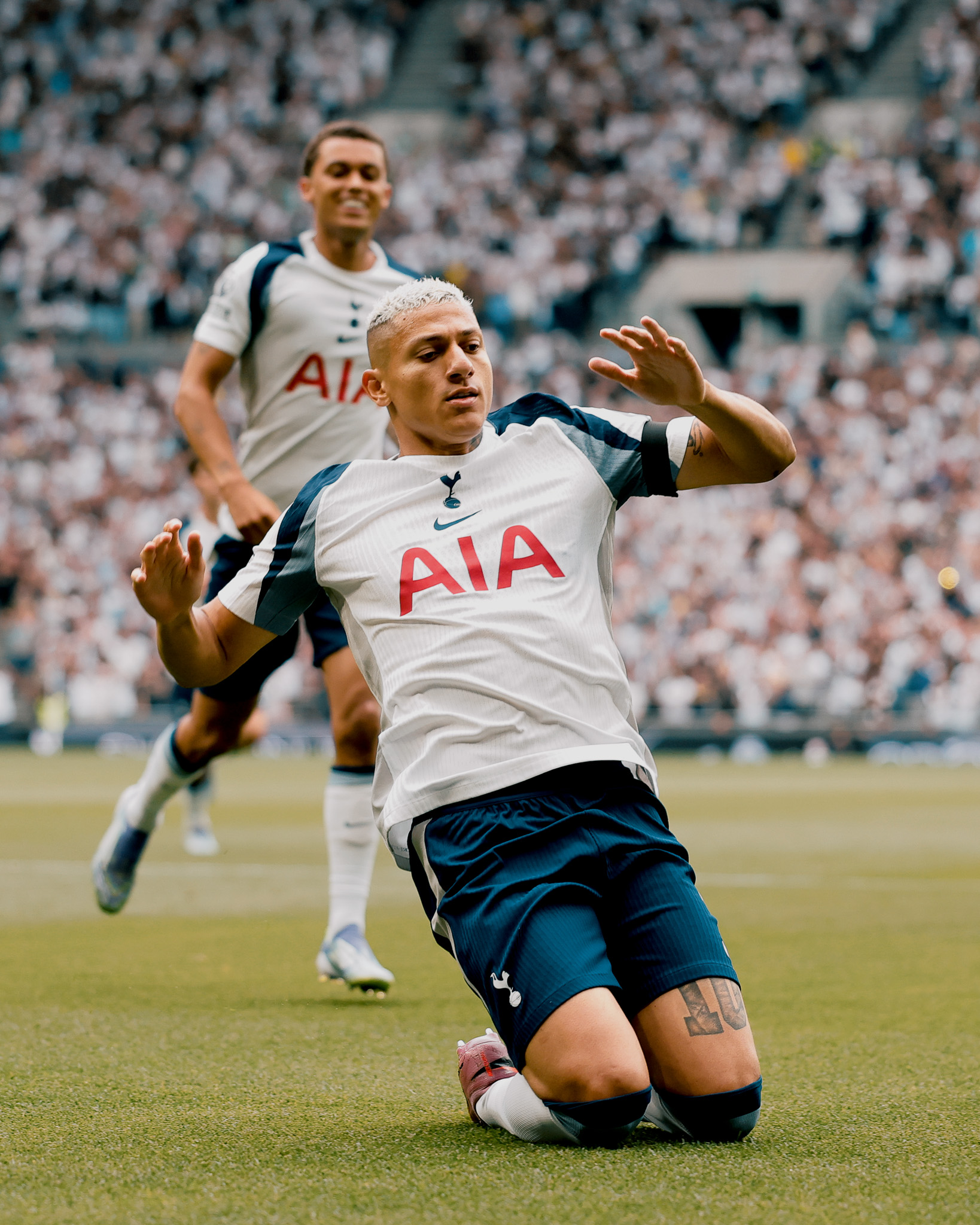 Richarlison does a knee slide goal celebration, with Brennan Johnson approaching behind him.