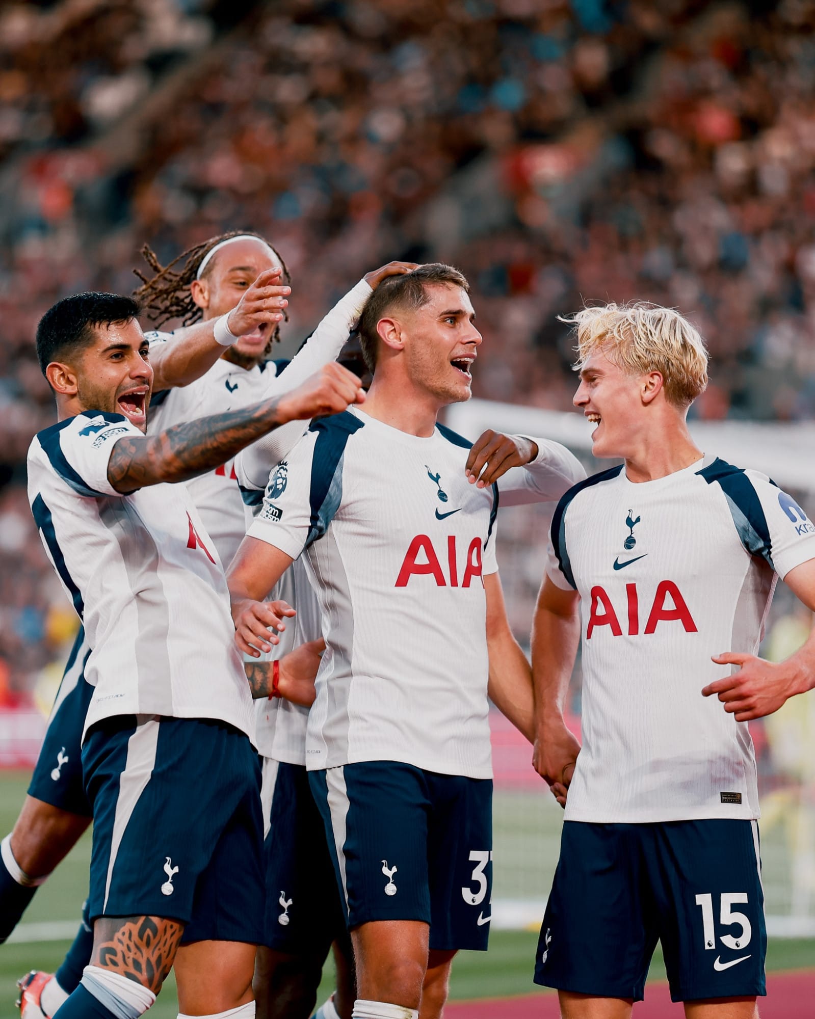 Micky van de Ven, smiling, is surrounded by his teammates after scoring. 