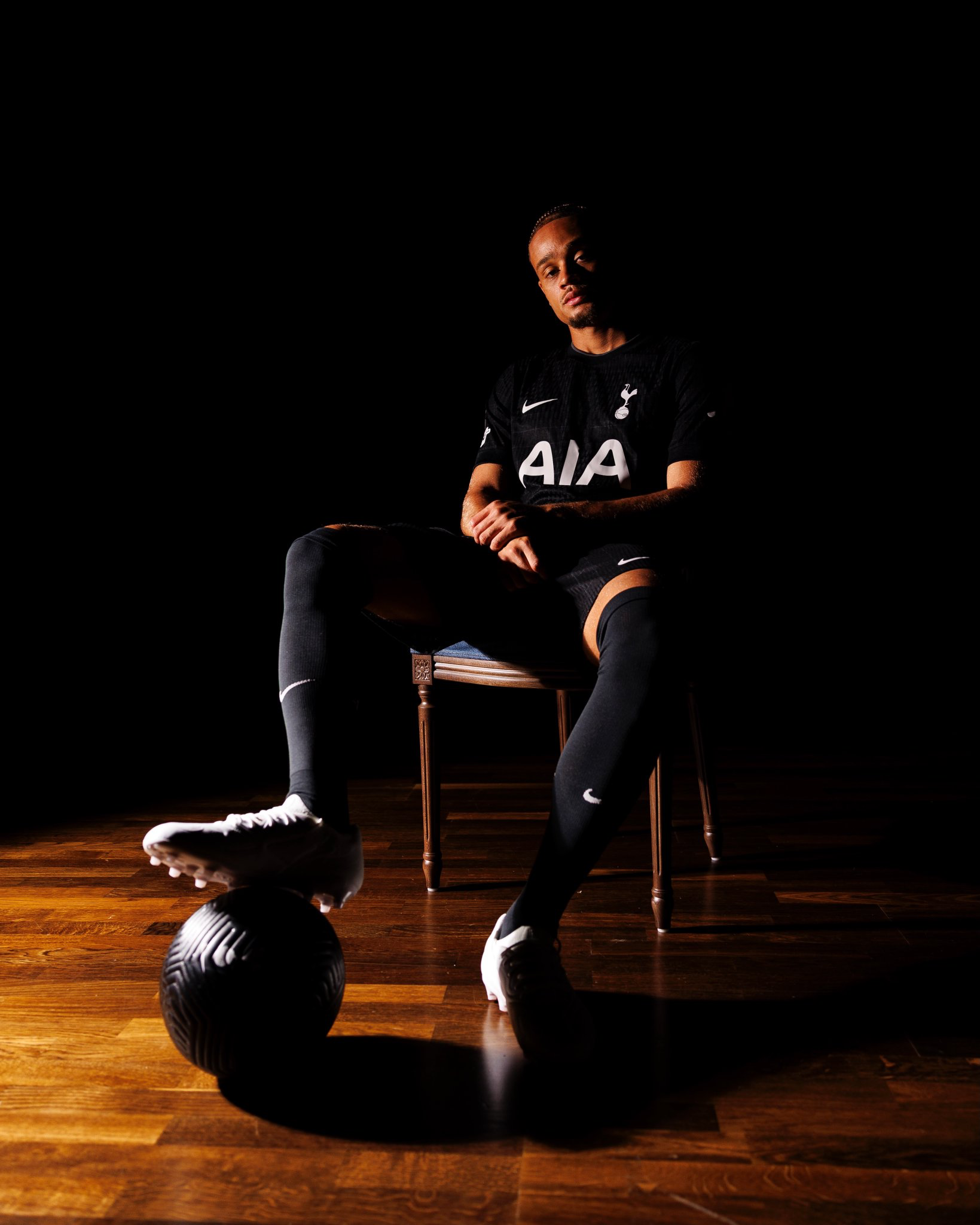 Xavi Simons sits in a chair with a football under his right foot.