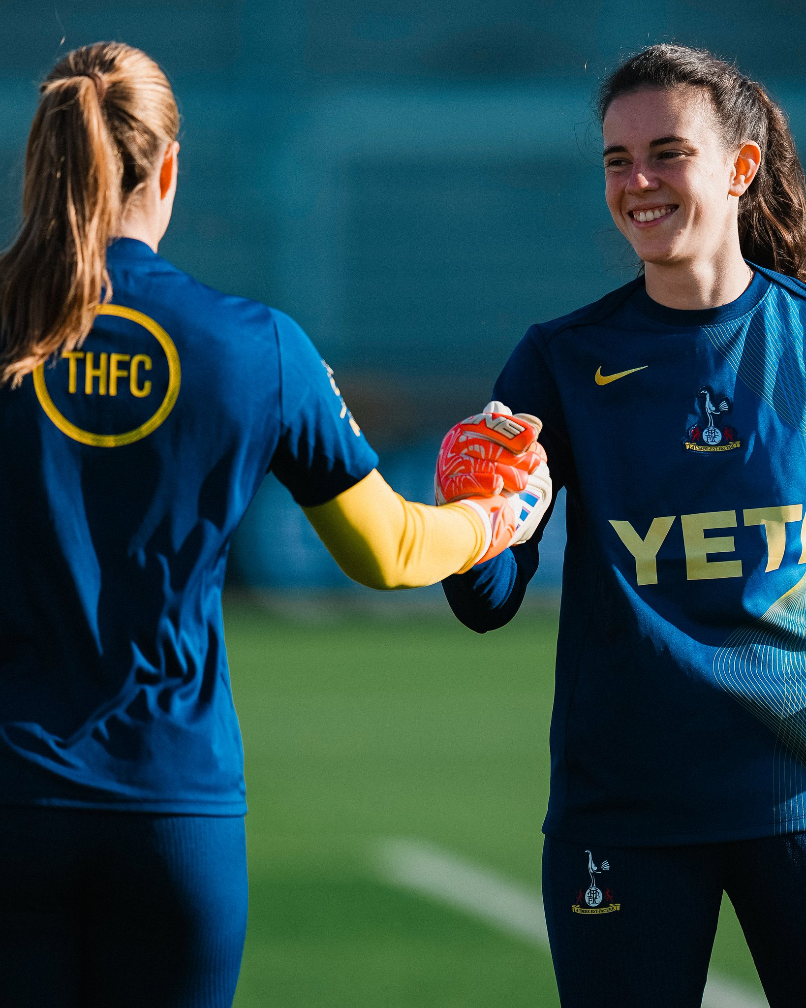 Lize Kop, with her back to the camera, shakes hands with Eleanor Heeps, both in training gear.