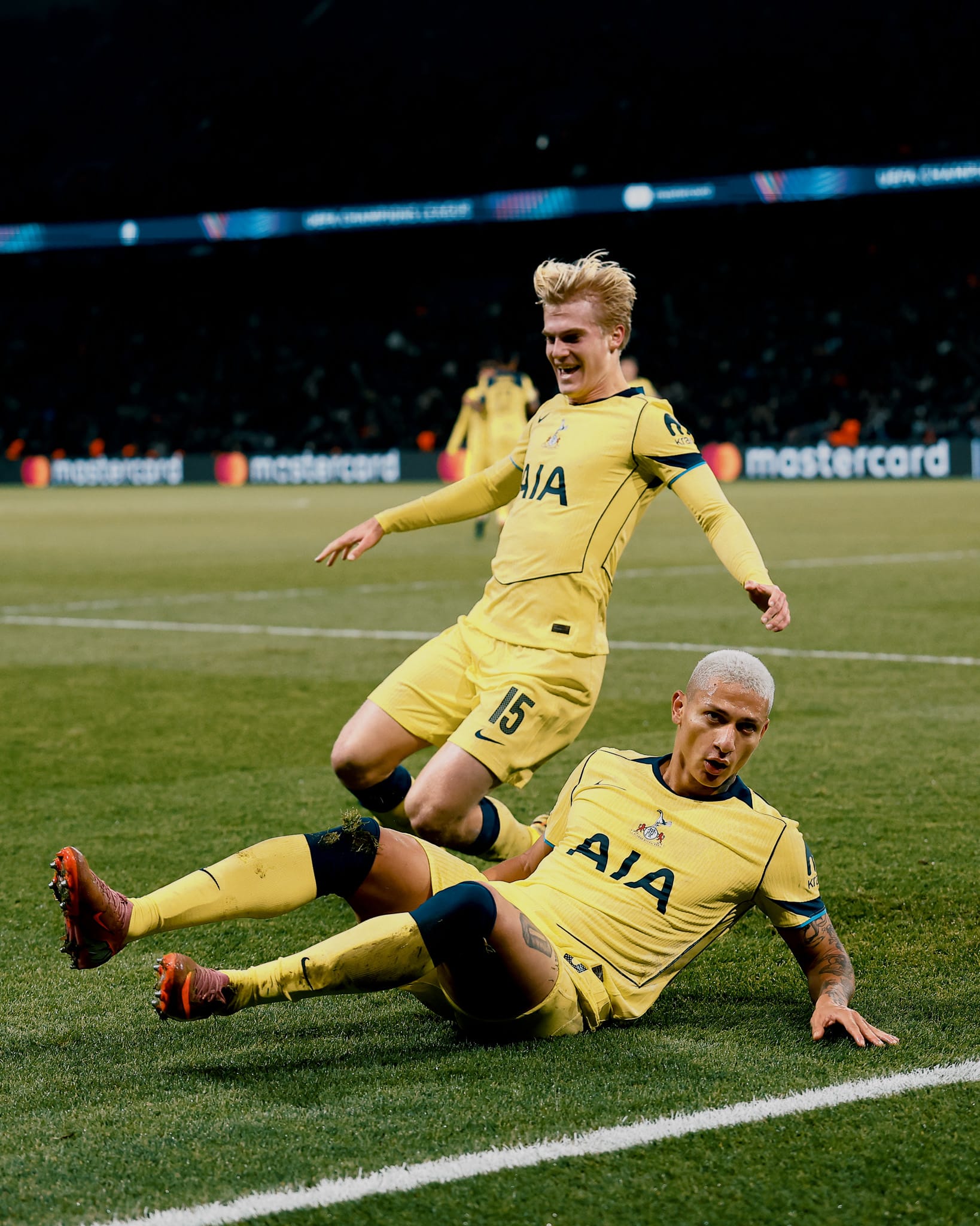 Richarlison slides to celebrate his goal, while Lucas Bergvall prepares to do the same behind him.