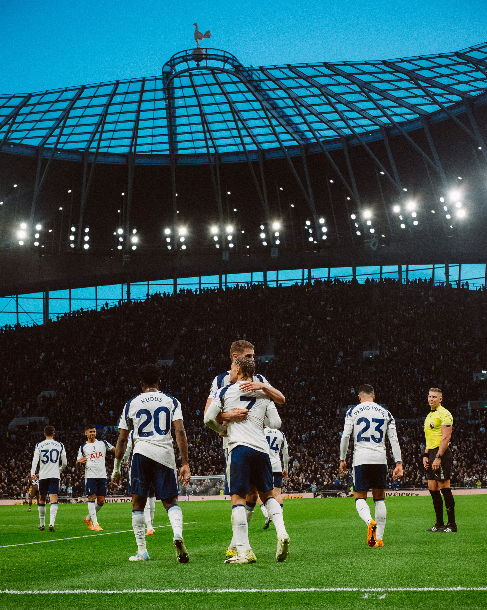 Micky van de Ven hugs Xavi Simons to celebrate the latter's first Spurs goal, the cockerel visible atop the stadium in the background.