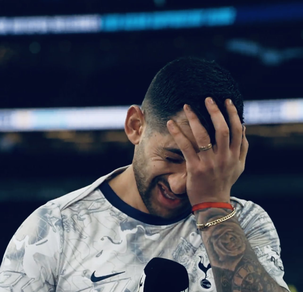 Cristian Romero holds his head in his hand adn grimaces during a post-game interview.