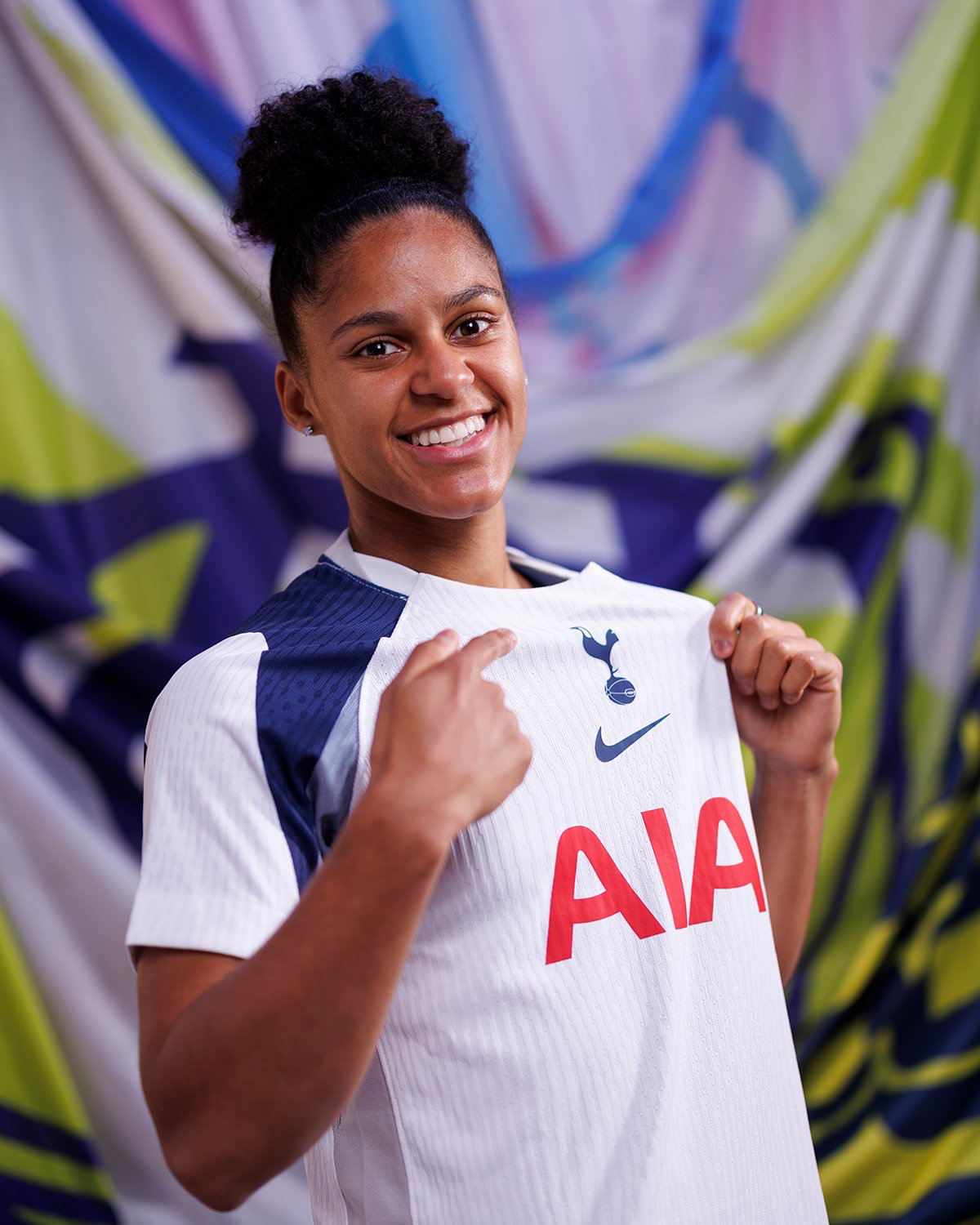 Shekiera Martinez smiles and points to the Spurs badge on her new kit.