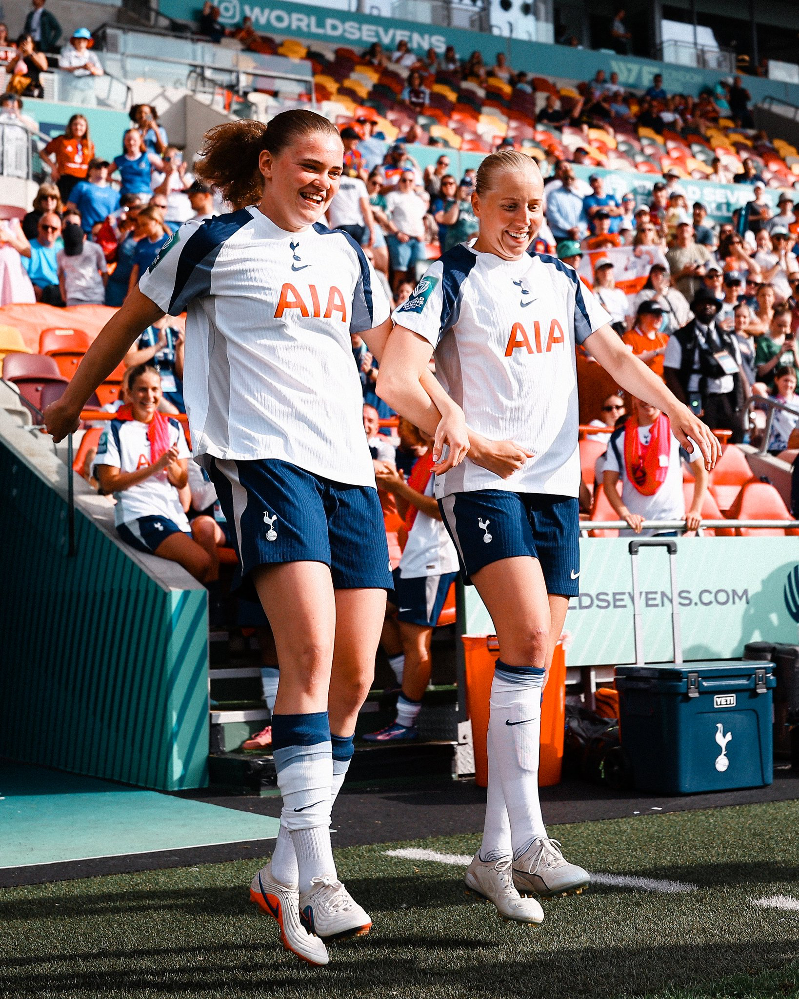 Signe Gaupset and Eveliina Summanen skip onto the pitch arm-in-arm.