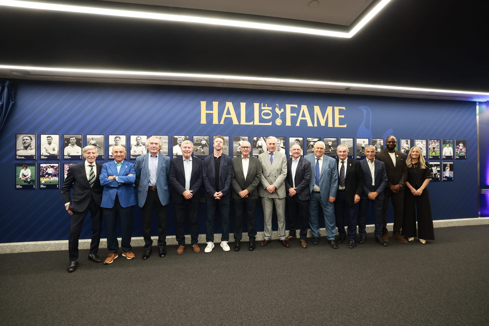 Former and new inductees to the Hall of Fame gather for a photo in front of the new wall instillation.
