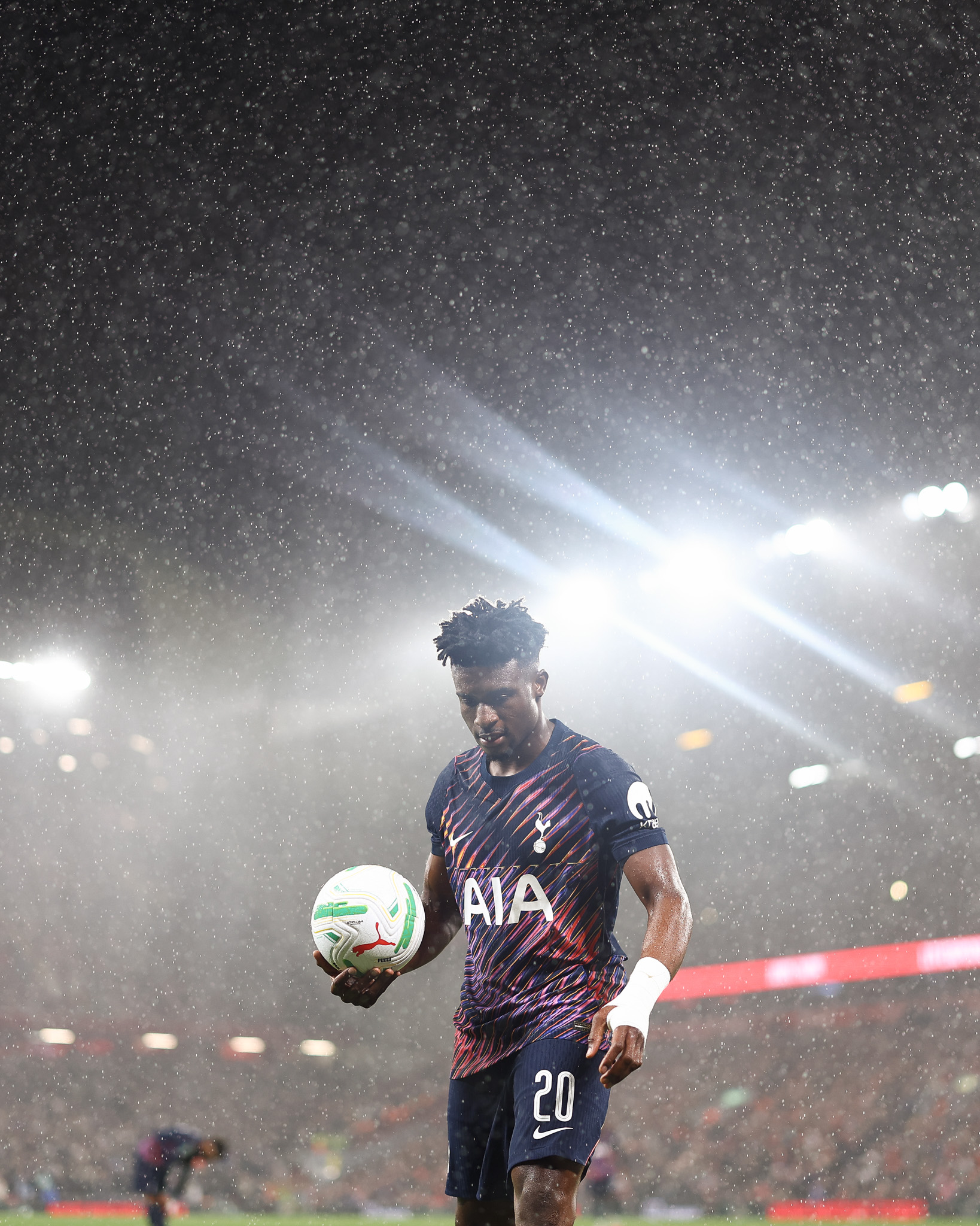 Mohammed Kudus holds the ball in his hands, heavy rain in the background.