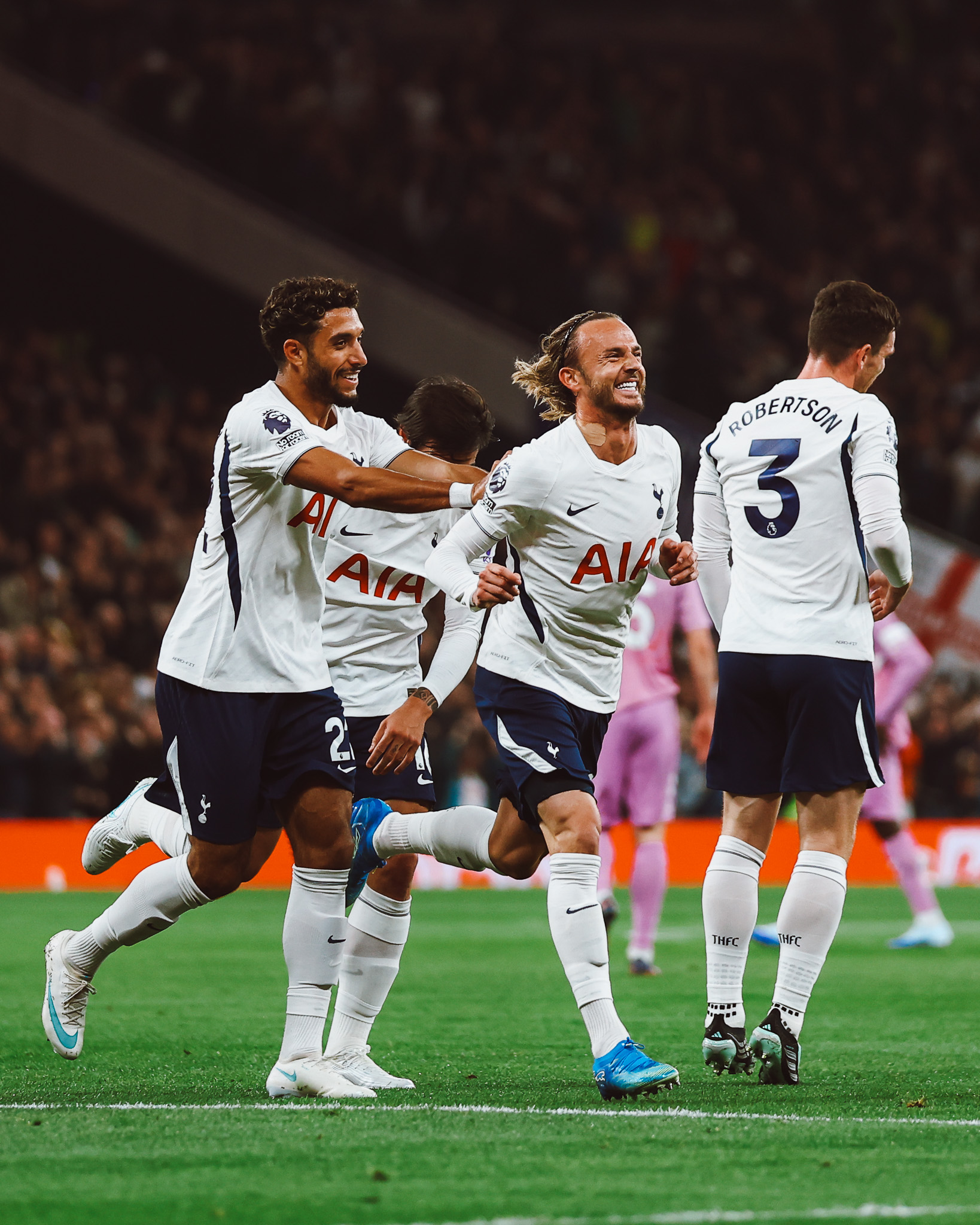 James Maddison beams after scoring a goal, surrounded by teammates.