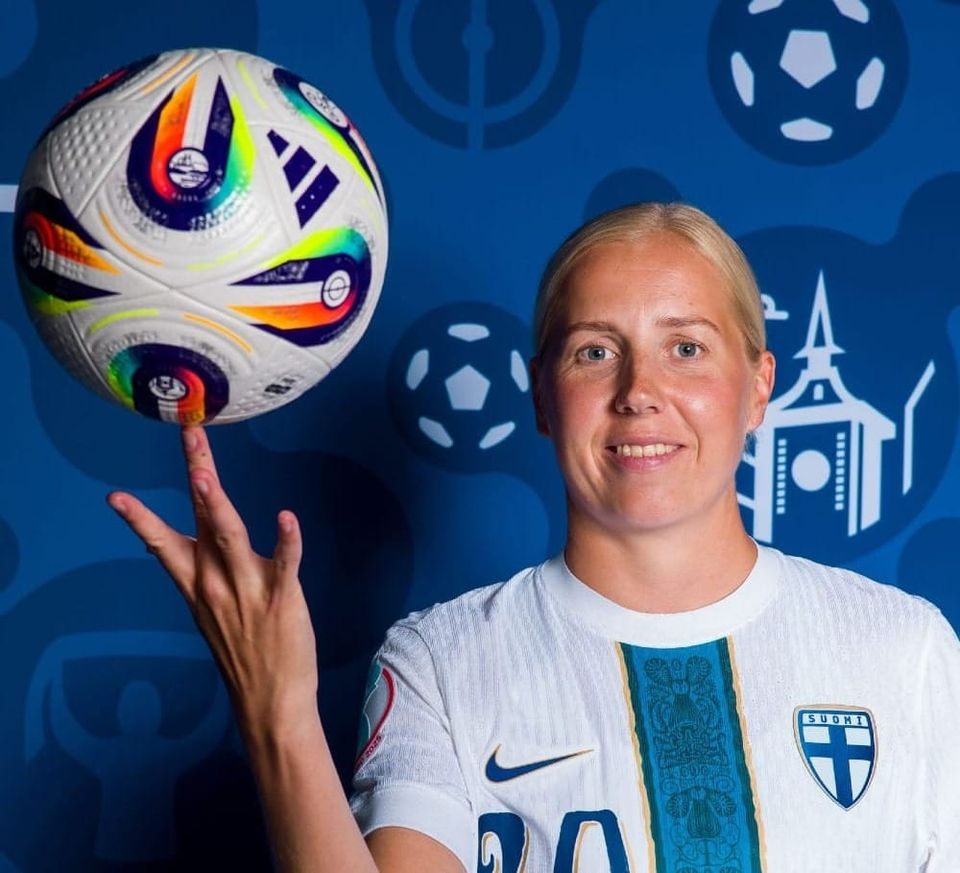 Eveliina Summanen spins a soccer ball on her finger and smiles in her Finland kit.
