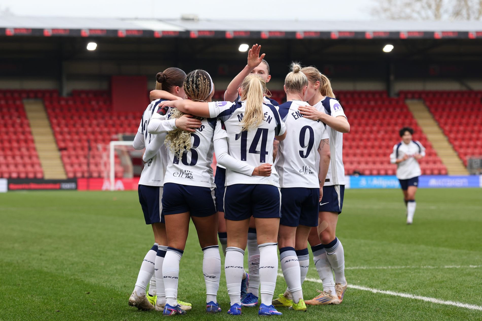 Spurs Women players huddle to celebrate a goal.