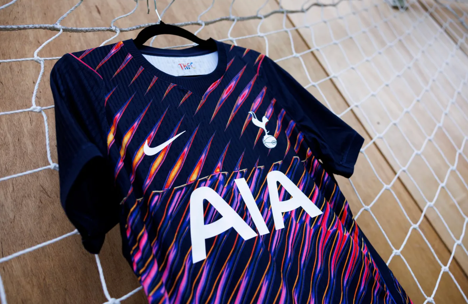 The new away kit hung up on a hang on a soccer net against a wooden wall.