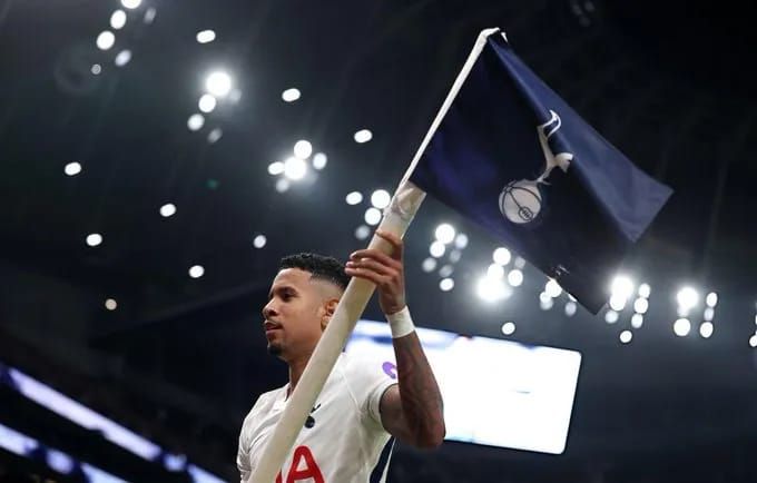 Sávio holds the Tottenham badge corner flag aloft.
