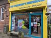 article headline: Ten years on, The Ferret is still digging — and looking ahead alt text: A bright yellow shopfront with blue