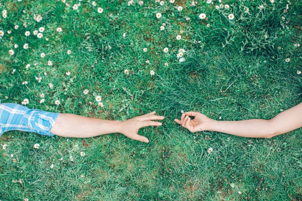 Two hands reaching toward each other, warm and tender, against a soft blurred background.