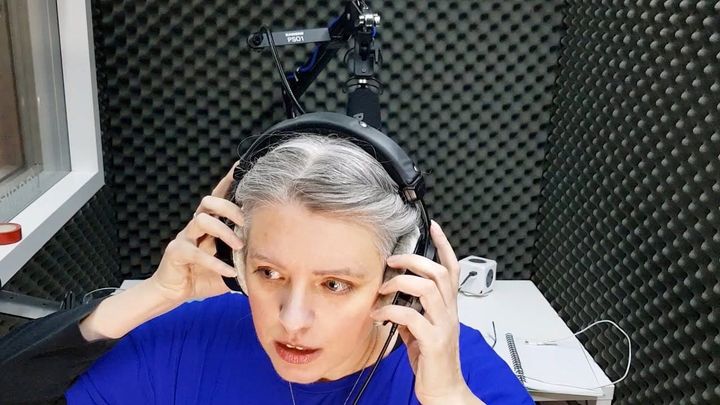 Emma Newman, wearing headphones inside a heavily sound-insulated recording booth