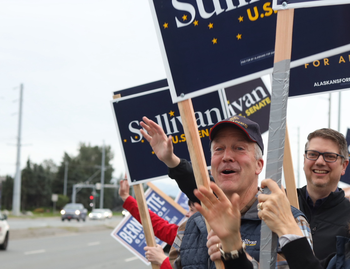 U.S. Sen. Dan Sullivan, center, and Nick Begich III wave signs at an Anchorage intersection in August. (Nathaniel Herz/Anchorage Press)
