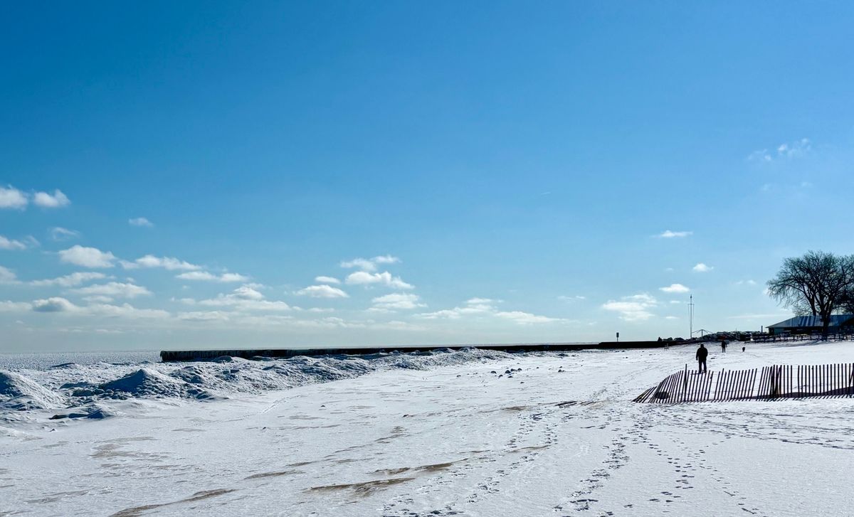 Winter beach scene on Lake Michigan. Snow and solitary figure walking.