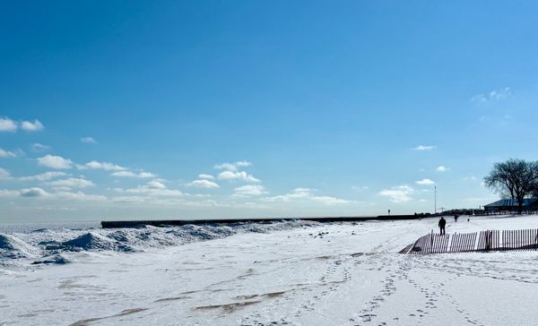 Winter beach scene on Lake Michigan. Snow and solitary figure walking.