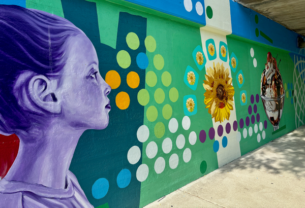 Mural at railroad underpass. Young woman, sunflower, ice cream sundae.