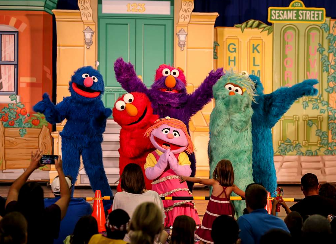 Sesame Street characters performing on stage in front of children
