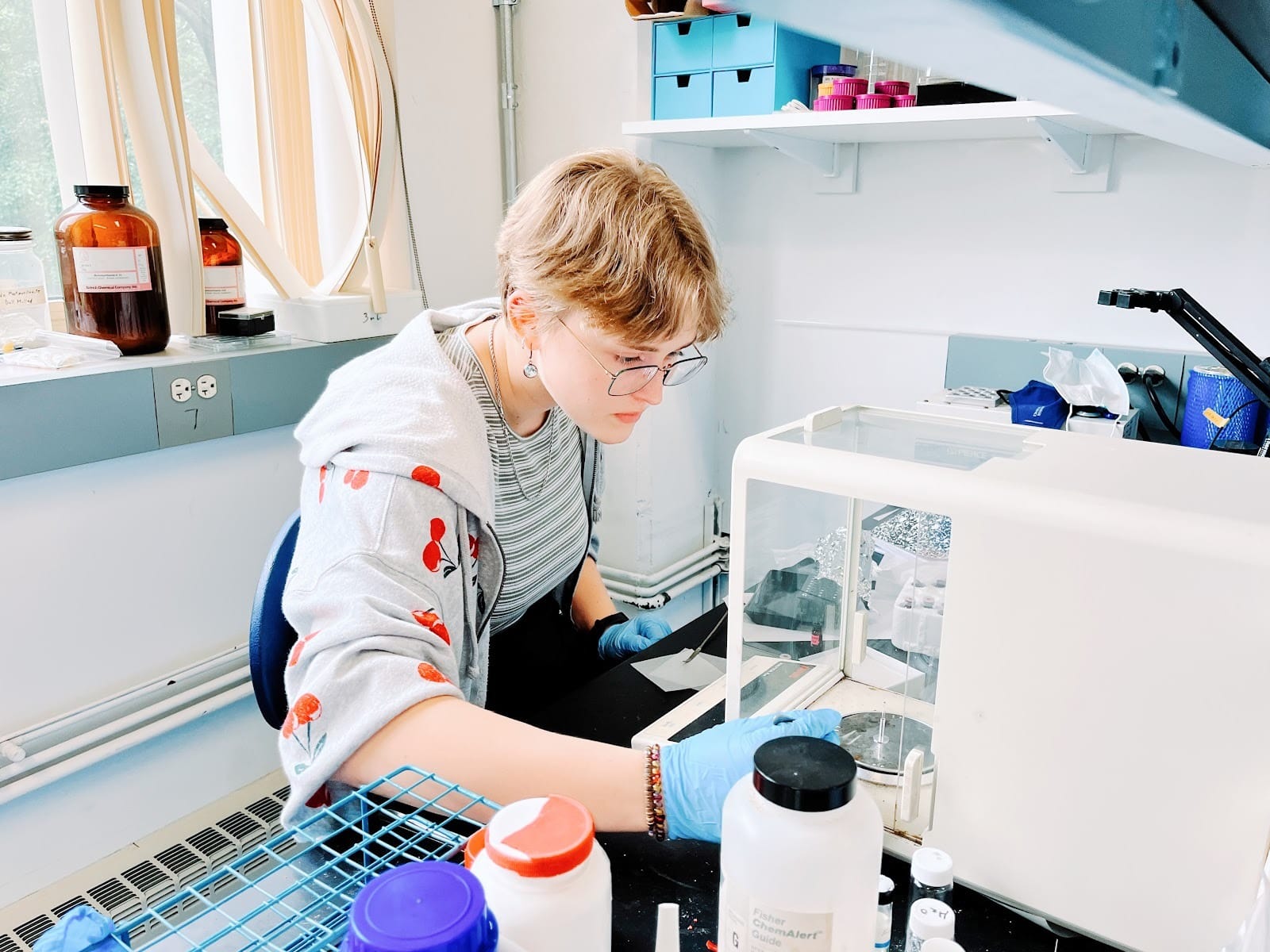 The author measures out chemicals in an enclosed mass balance in a laboratory.