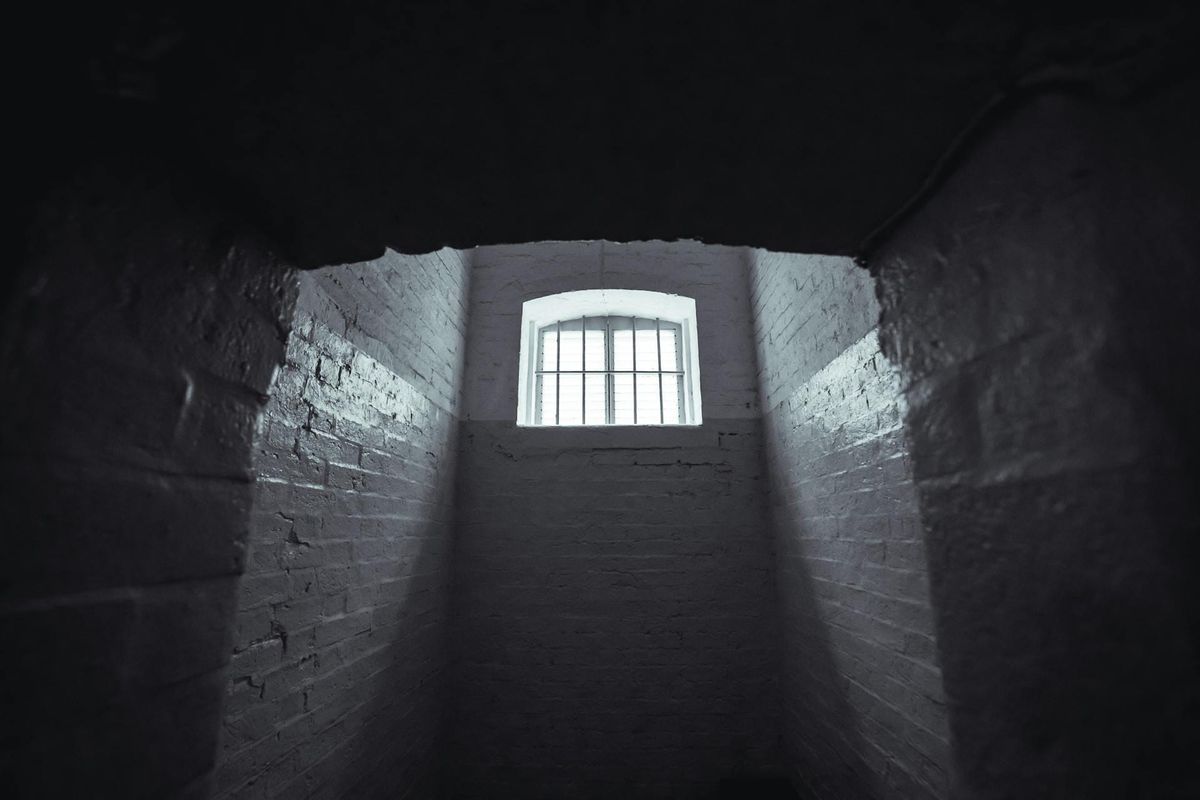 The insides of a prison cell, with a single a barred window