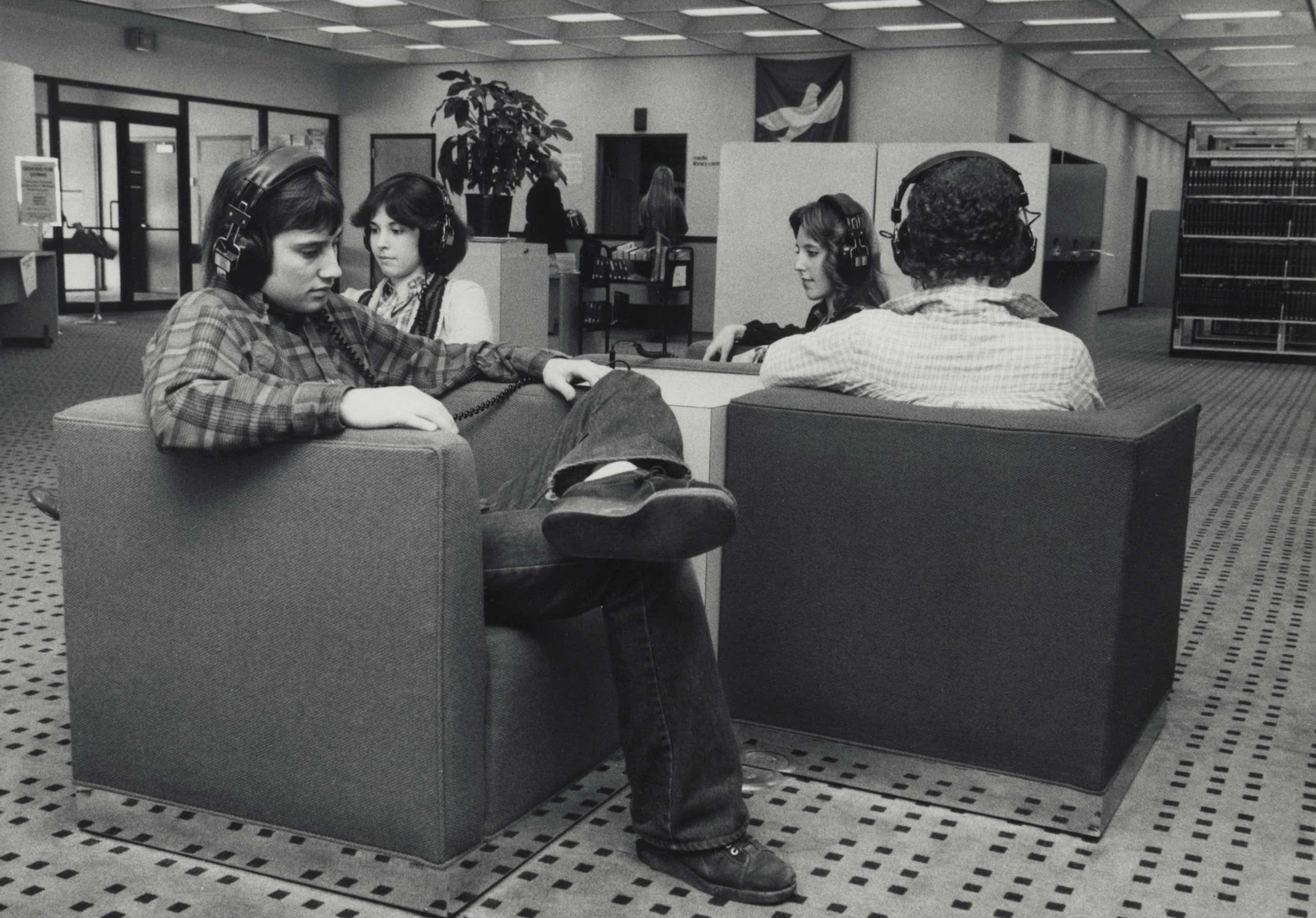 Patrons sitting in a library with headphones on listening to music
