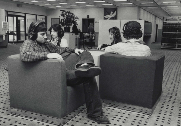 Patrons sitting in a library with headphones on listening to music