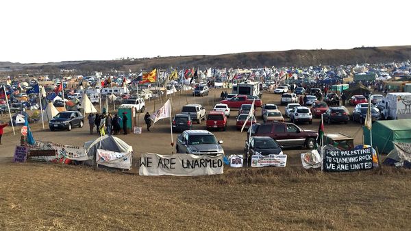 A campground filled with cars, flags, and signs that read WE ARE UNARMED