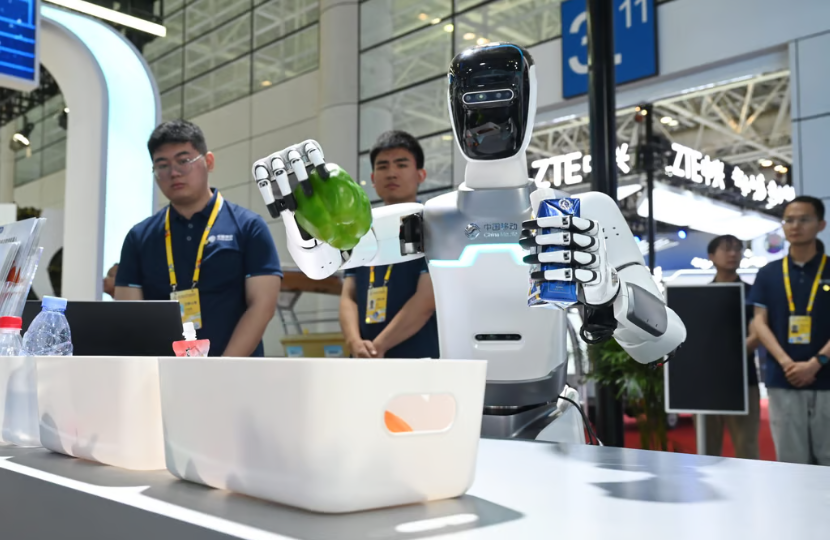 Humanoid robot demonstrating AI automation at a tech event in Beijing's Yizhuang Development Zone, with attendees observing in the background.