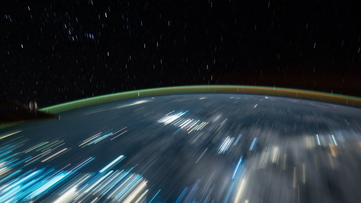 Long-exposure photograph of Earth at night from the International Space Station, city lights streaked by the station's motion