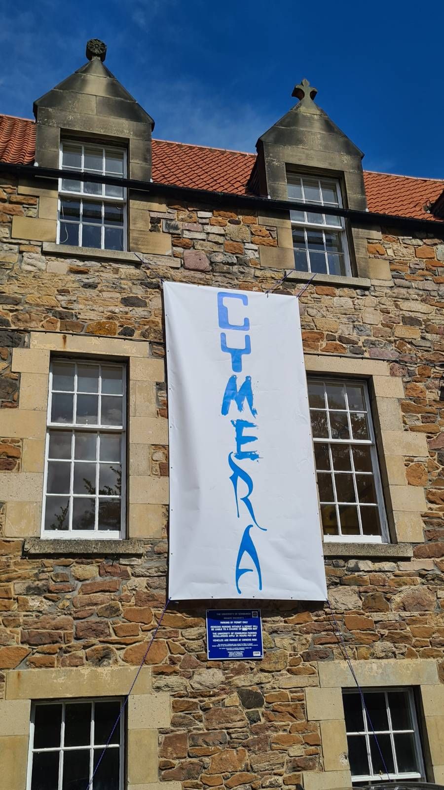 Old Edinburgh building with rough cut sandstone, 4 windows and white banner with blue Cymera logo hanging from building