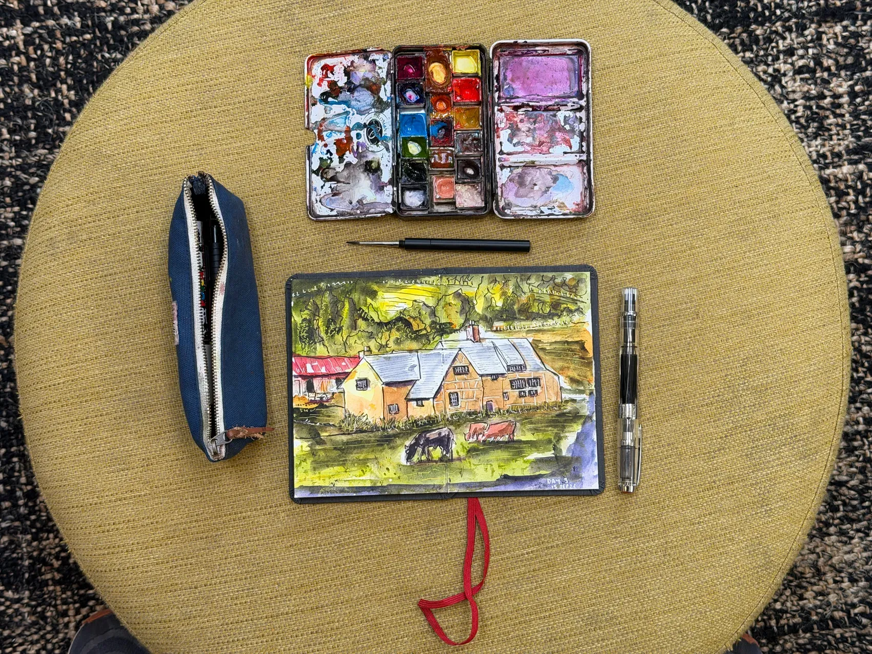 The sketchbook, open watercolour palette, brush, fountain pen and pencil case used on the journey.