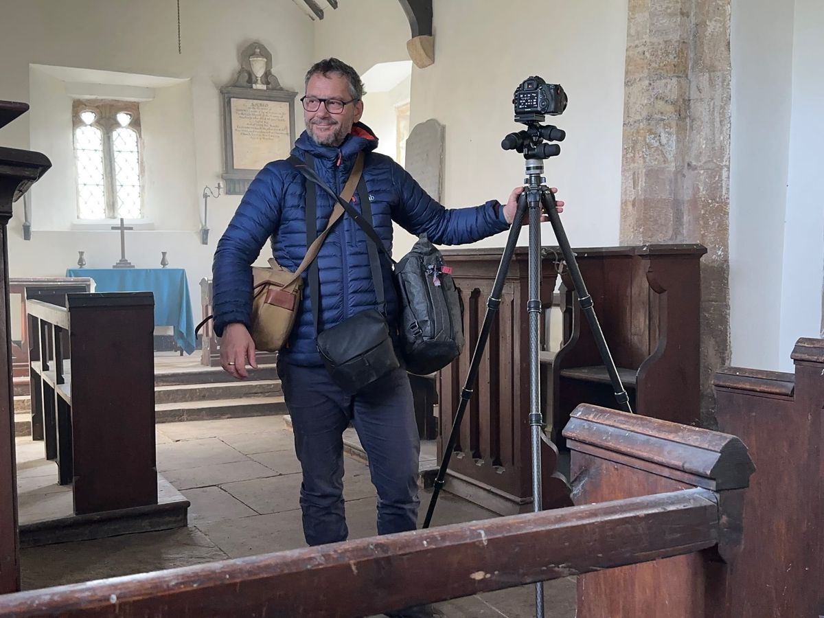 Andy standing with his camera and tripod inside a church.