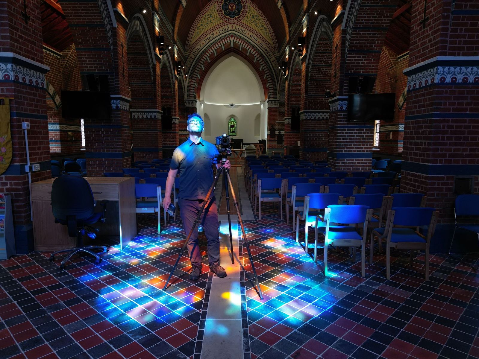 Andy Marshall standing with his tripod in coloured stained-glass light
