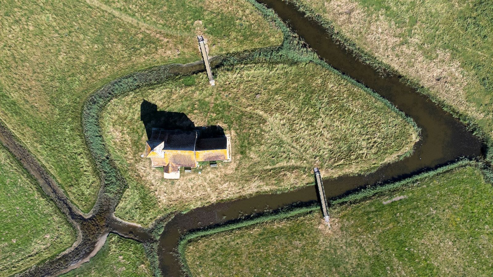 An isolated church embraced by winding waterways from above