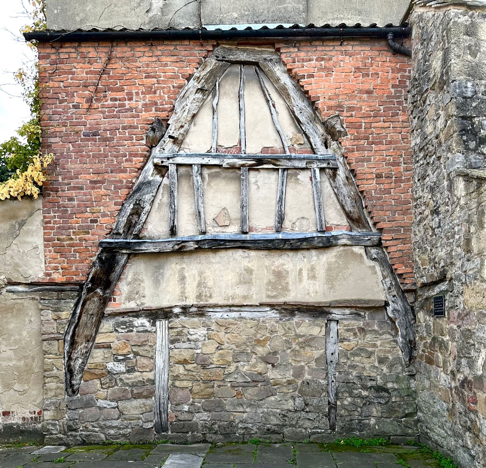 The timber outline of a vanished cruck-framed house preserved in a brick and stone gable at Wirksworth